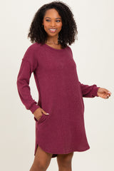 woman wearing a burgundy long sleeve ribbed dress with side pockets and a relaxed fit