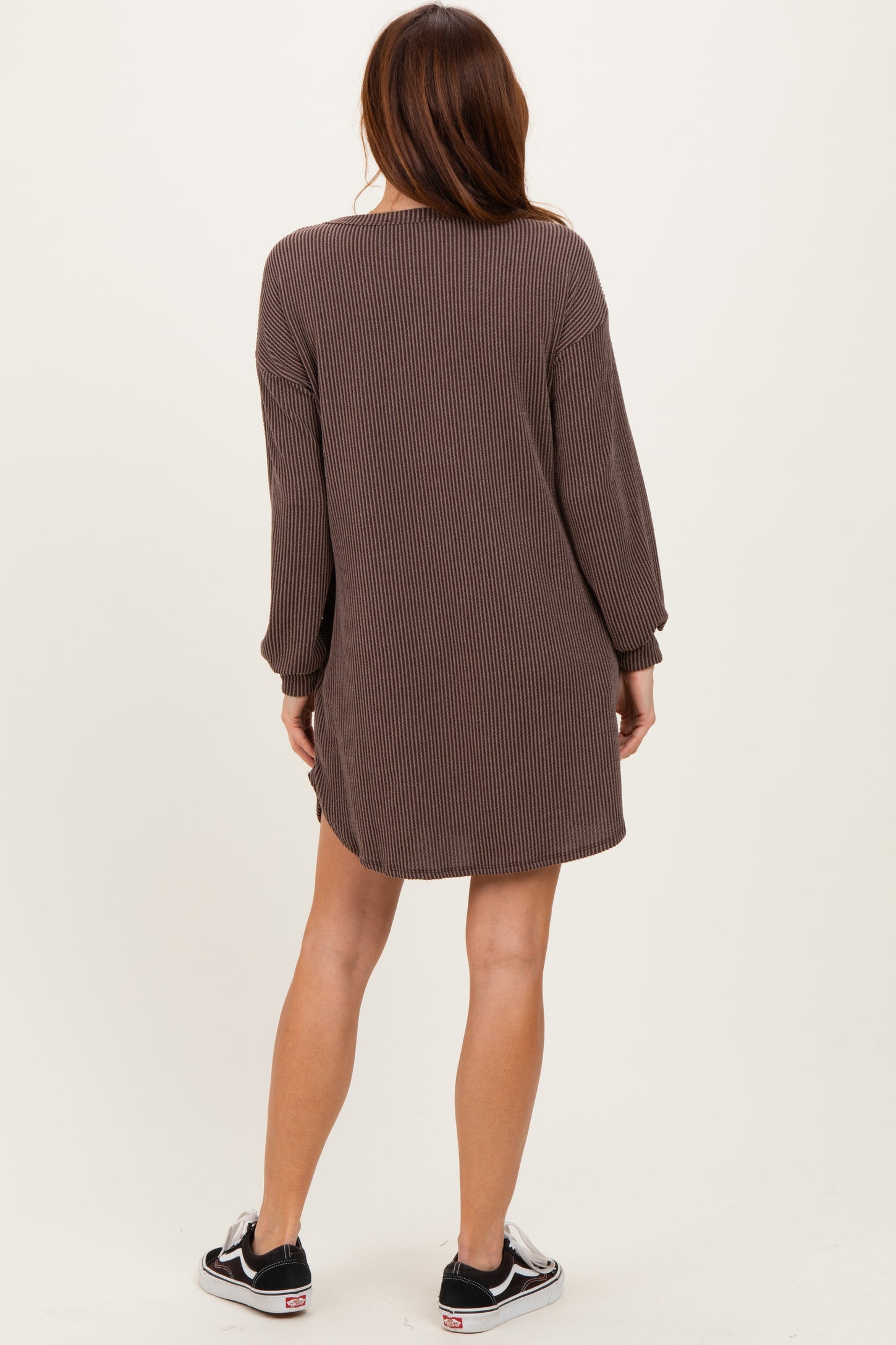woman wearing a brown striped long sleeve mini dress, shown from the back, paired with black sneakers
