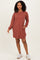 woman wearing a rust striped long sleeve casual dress with pockets and white sneakers