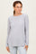 woman wearing a light gray long sleeve ribbed top with raglan sleeves and a rounded hem