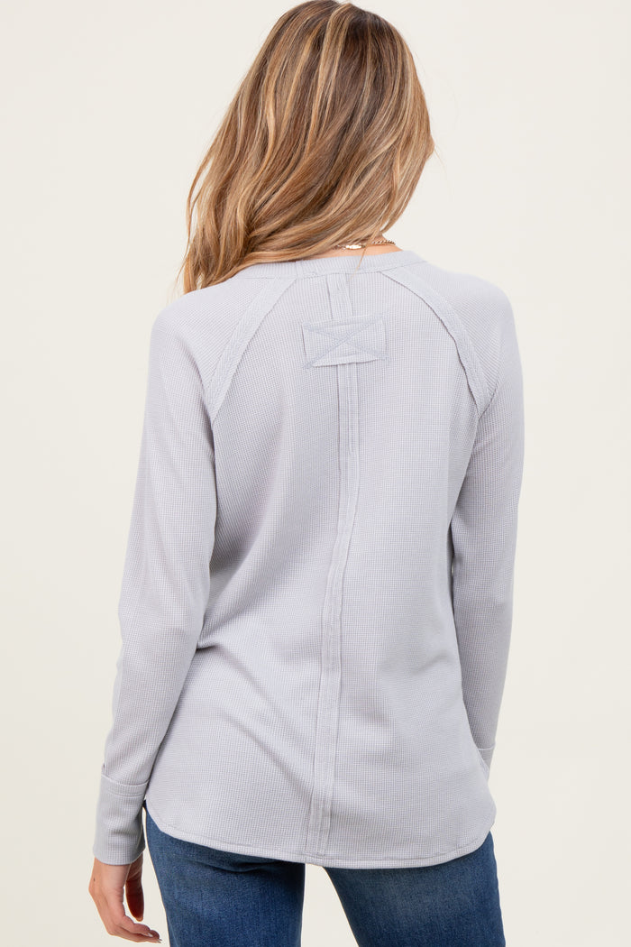 woman wearing a light gray maternity long sleeve top with a back bow detail and fitted style