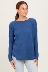 woman wearing a dark blue long sleeve ribbed top with a relaxed fit and side slits, posing with a neutral background