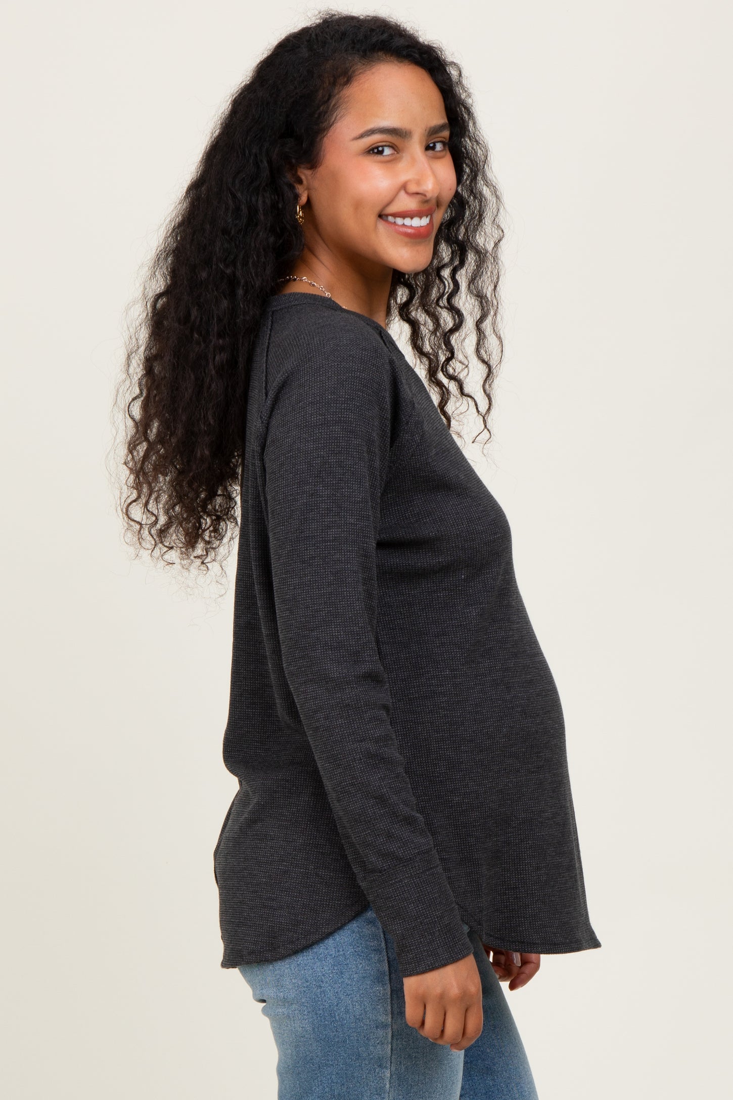 woman wearing a dark gray long sleeve maternity top and showing her baby bump