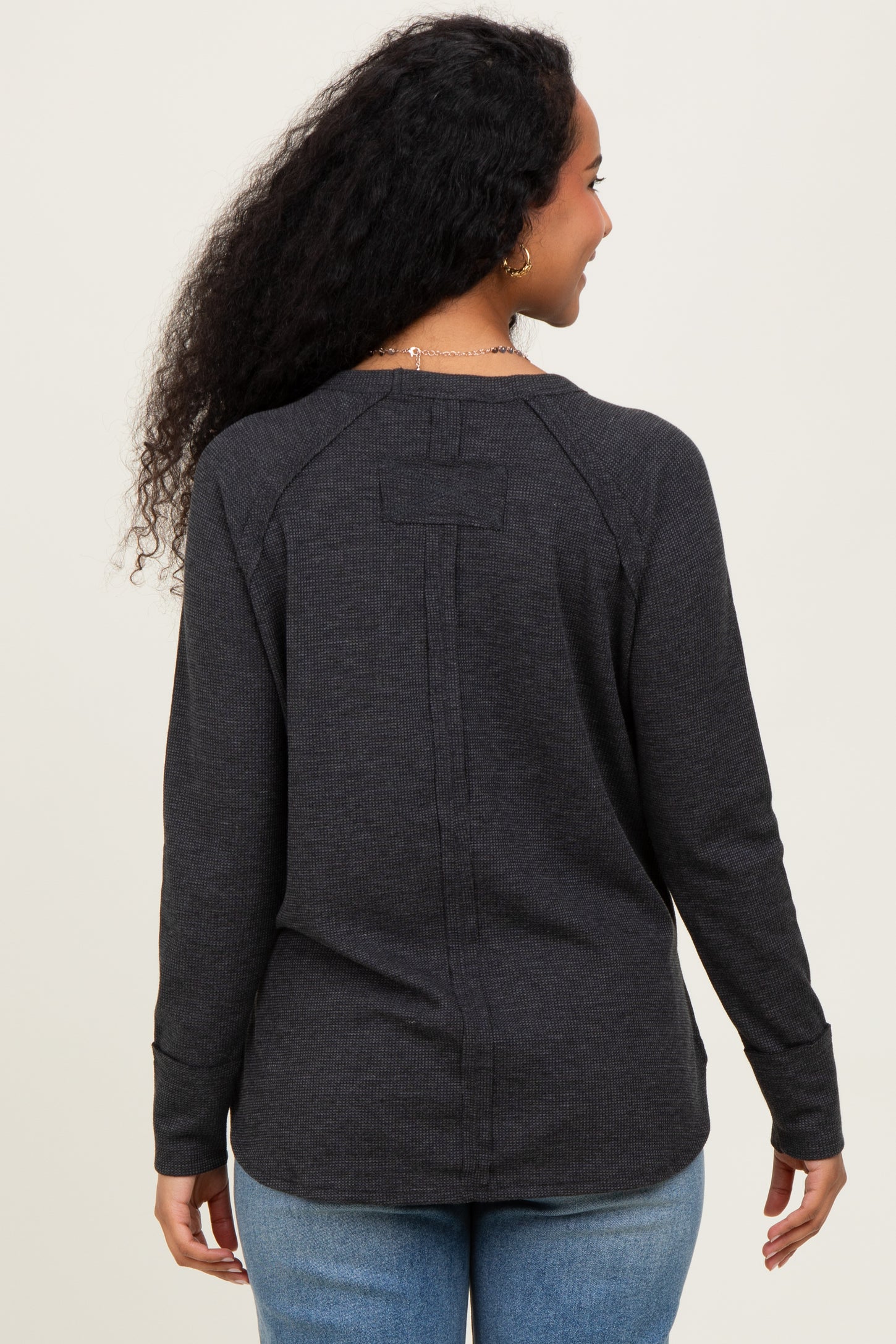 woman wearing a dark gray maternity long sleeve top, viewed from the back, with a relaxed fit and subtle seam details