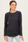 woman wearing a dark gray long sleeve ribbed top with raglan sleeves and a rounded hem, smiling at the camera
