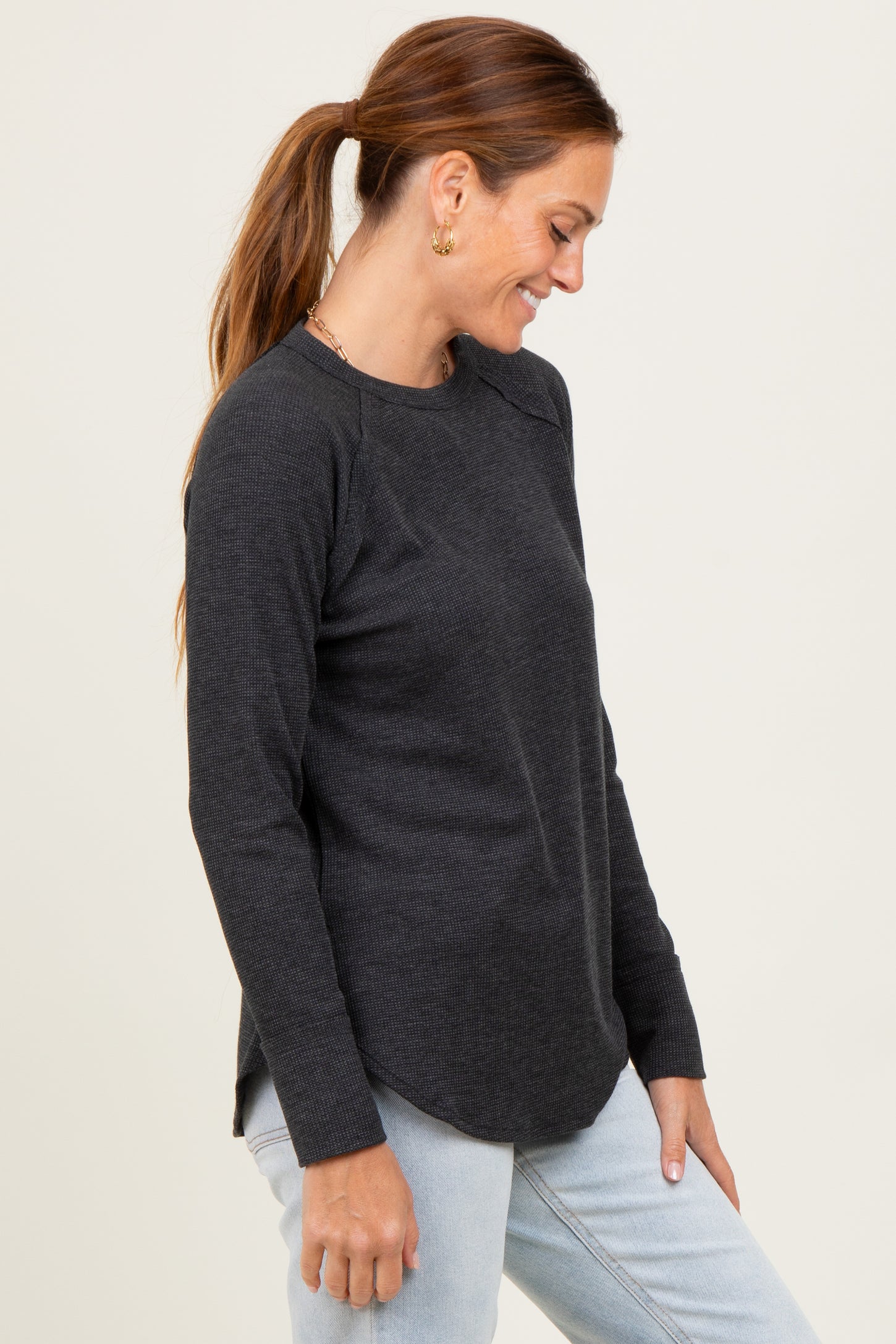 woman wearing a charcoal gray long sleeve ribbed top with side slits and a relaxed fit