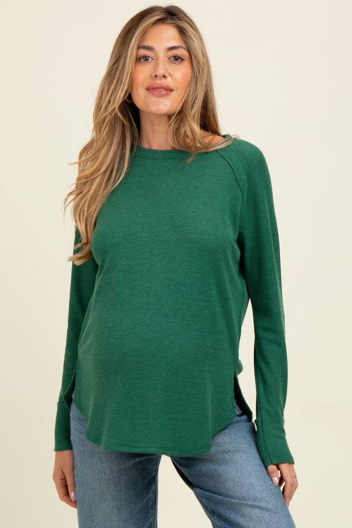 woman wearing a green long sleeve maternity top with a relaxed fit and side slits, showing her baby bump