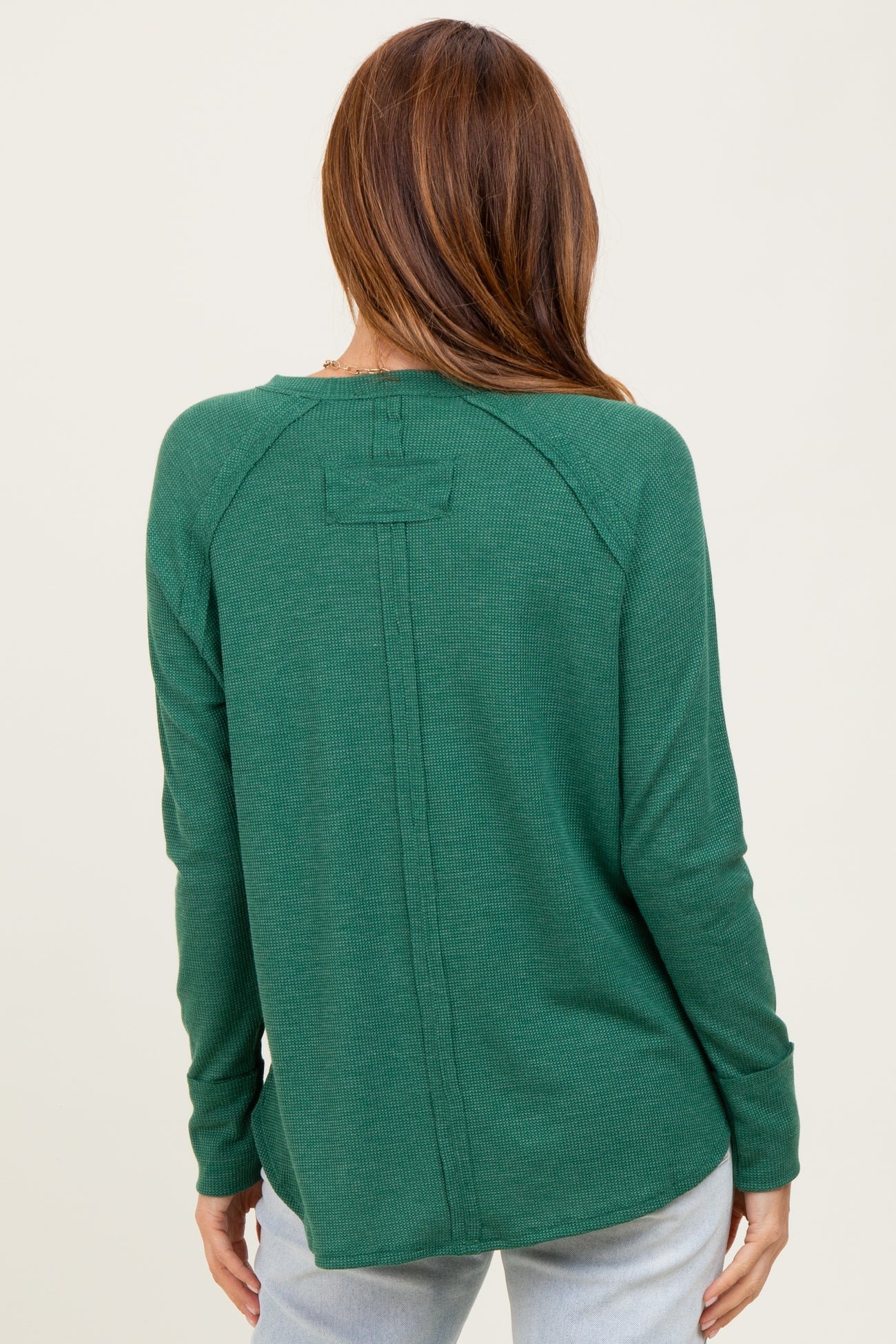 woman wearing a green long sleeve waffle knit top with a back seam detail