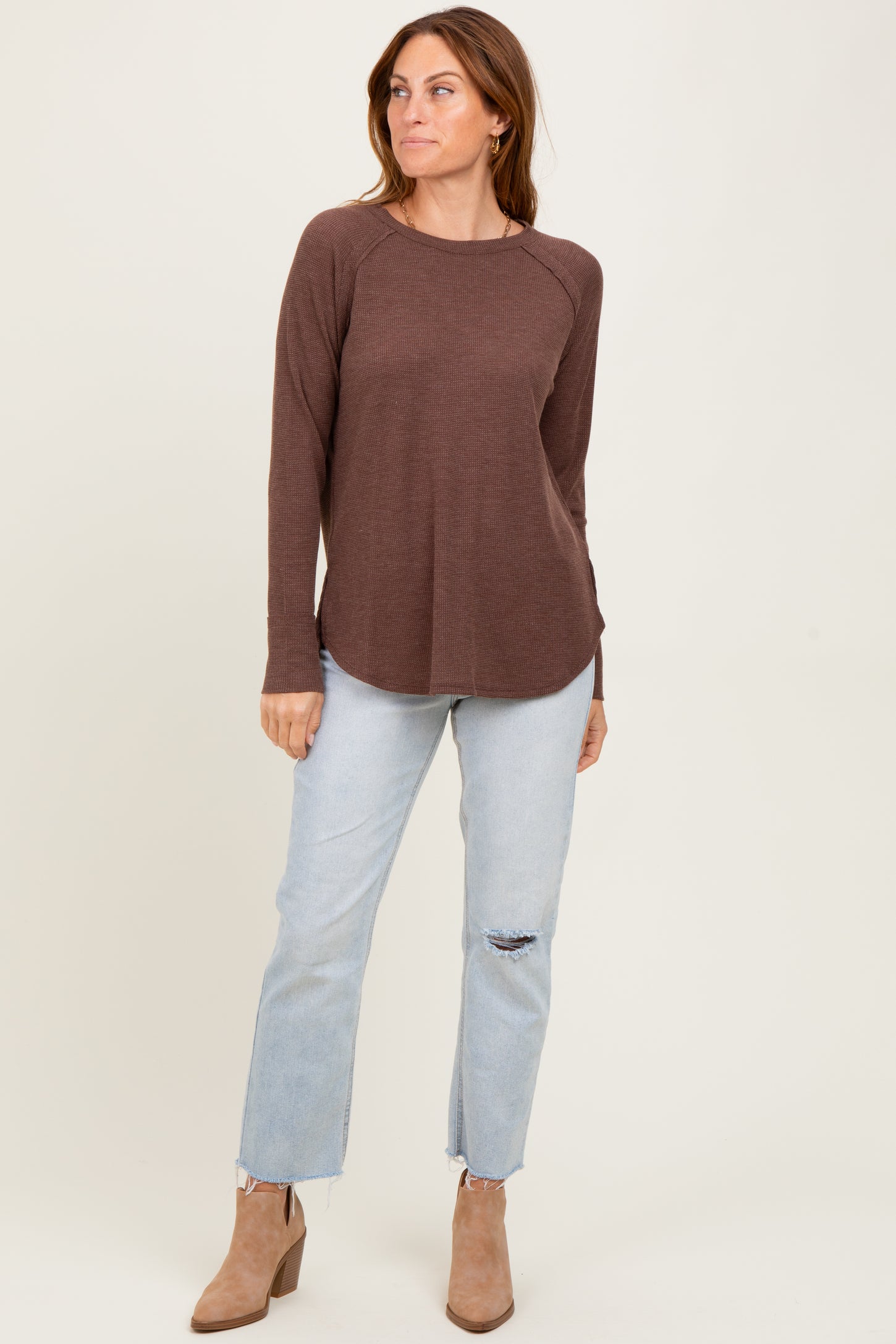 woman wearing a brown long sleeve ribbed top with a relaxed fit and light blue distressed jeans