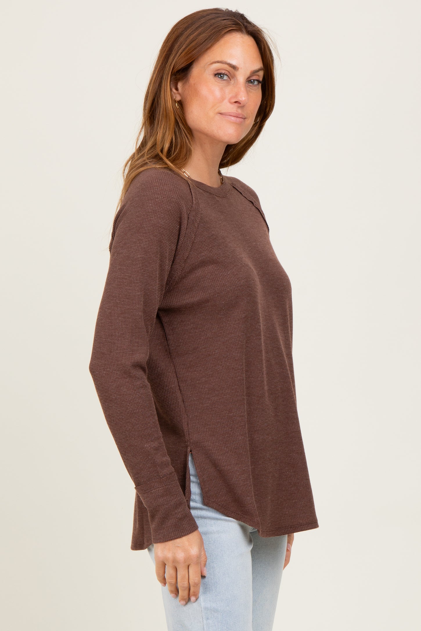 woman wearing a brown long sleeve ribbed top with side slits and a relaxed fit