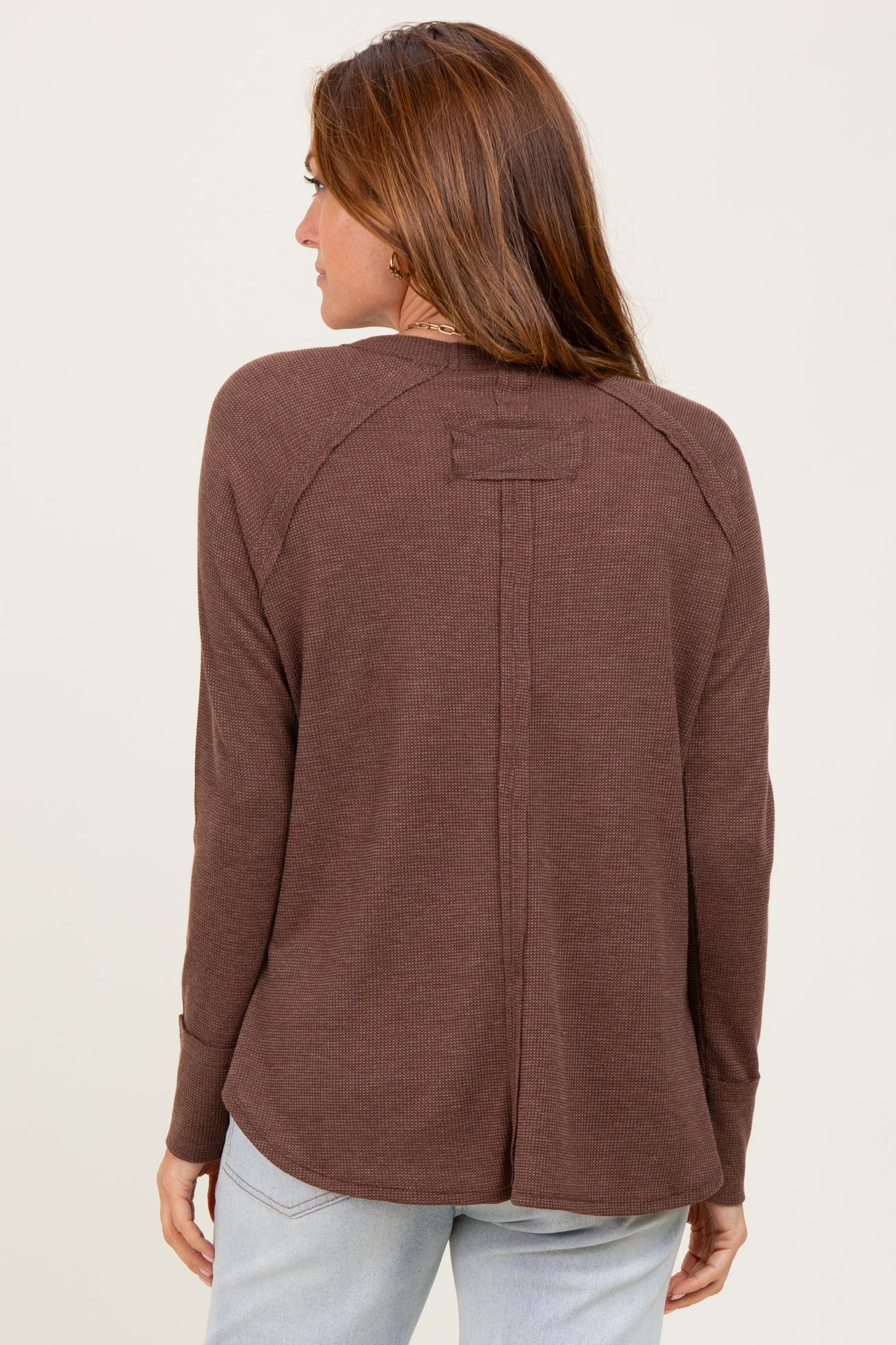woman wearing a brown long sleeve top with a relaxed fit and a back seam detail