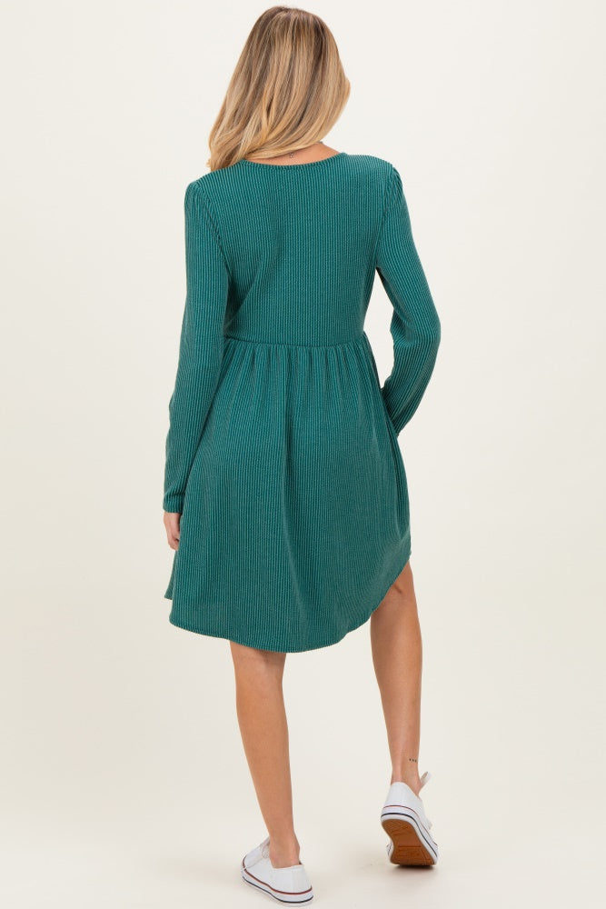 woman wearing a green ribbed long sleeve maternity dress with a flared skirt, showing a baby bump from behind