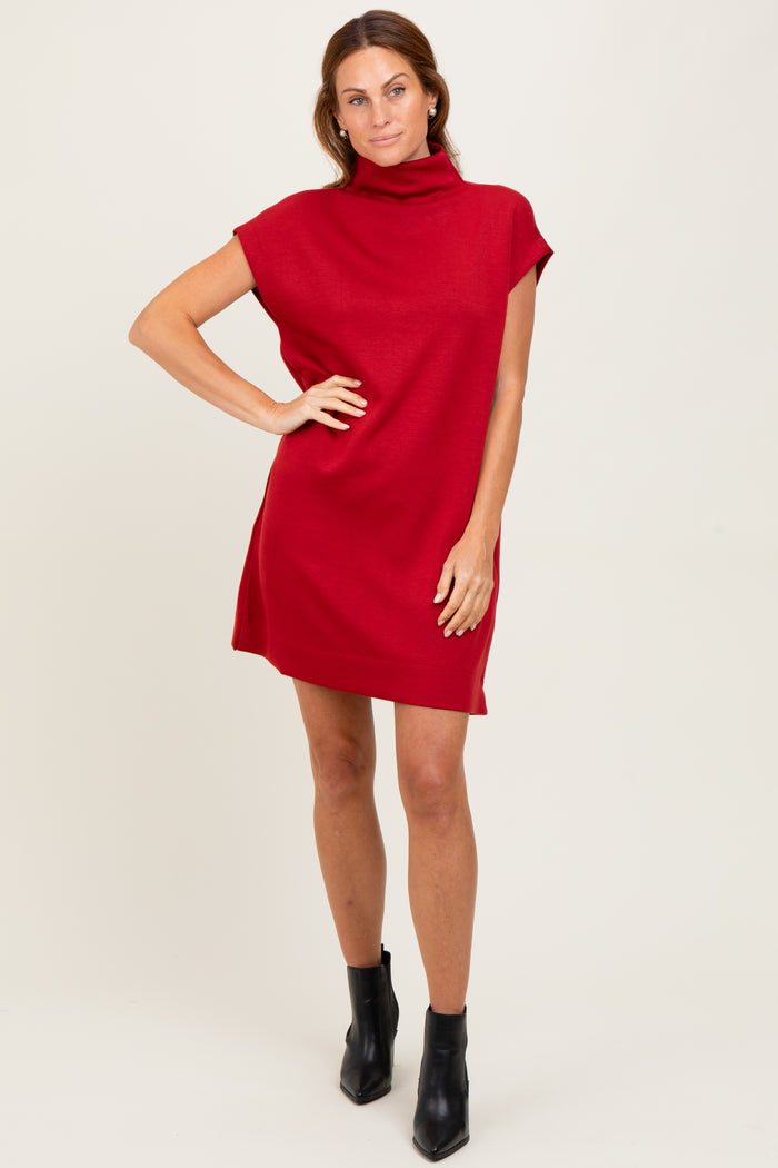 woman wearing a red short sleeve turtleneck dress and black ankle boots