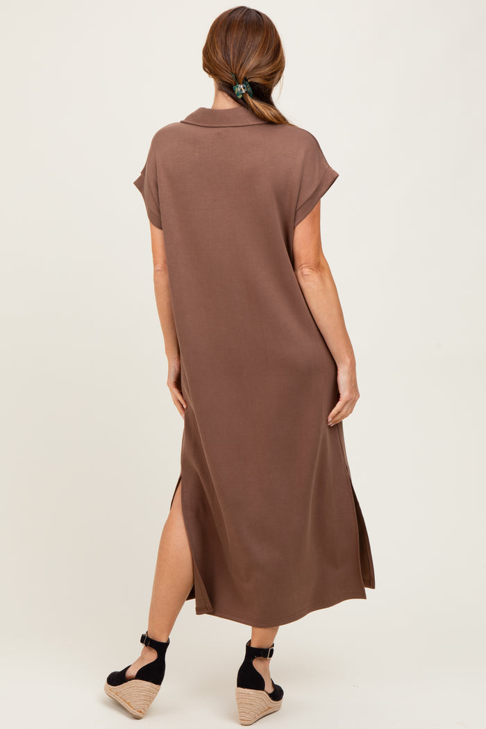 woman wearing a brown short sleeve maxi dress with side slits and a collar, standing with her back to the camera