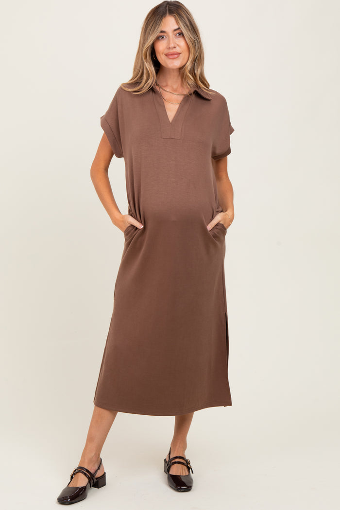 woman wearing a brown short sleeve maternity dress with pockets and side slits, holding her baby bump