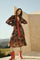 woman wearing a floral long sleeve dress with a tie front and red accents, paired with knee-high boots