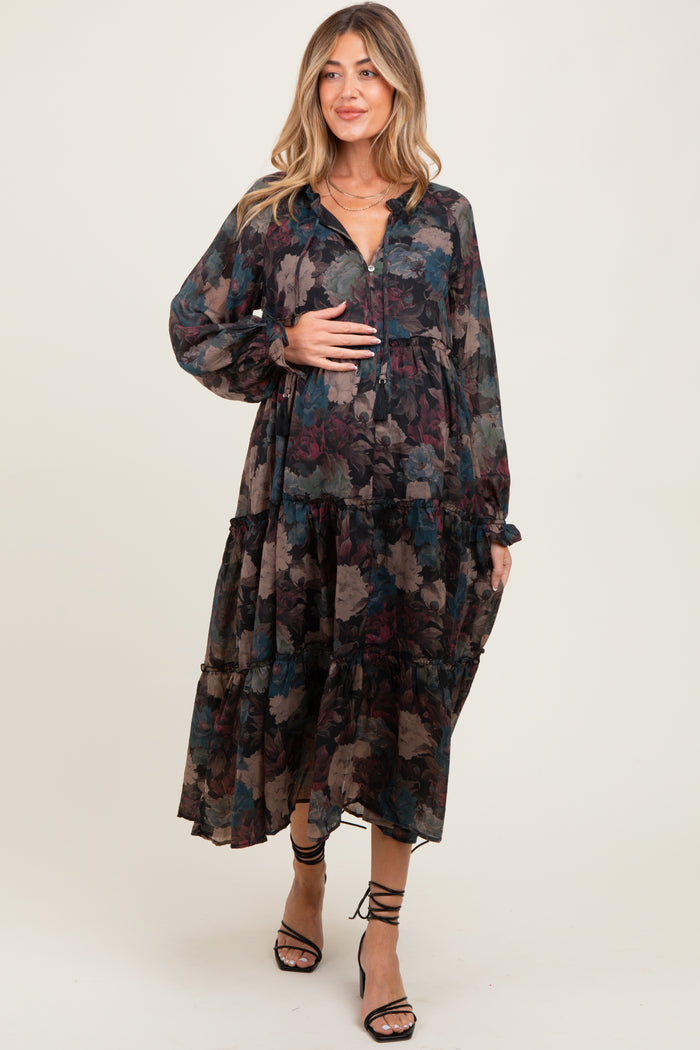 woman wearing a floral print long sleeve maternity dress with a tiered design and holding her baby bump
