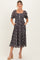 woman wearing a black floral maternity dress with puff sleeves, a square neckline, and pockets, showcasing her baby bump