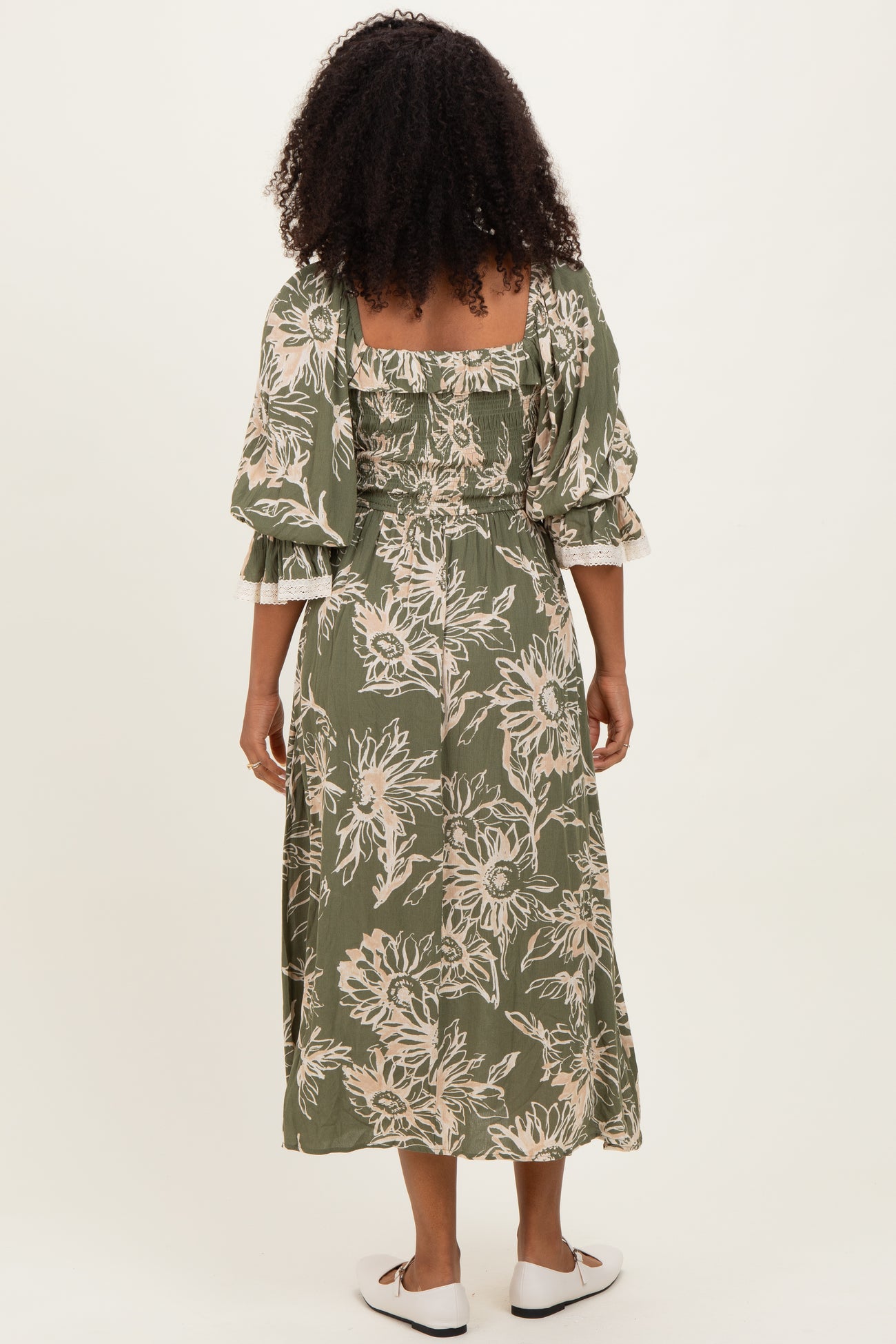woman wearing an olive green floral midi dress with puff sleeves and a fitted bodice, shown from the back