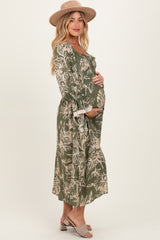 woman wearing a green floral maternity dress with a flowy silhouette and holding her baby bump