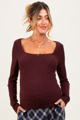 woman wearing a burgundy ribbed maternity top with a square neckline and long sleeves, styled with a relaxed fit