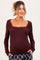 woman wearing a burgundy ribbed maternity top with a square neckline and long sleeves, styled with a relaxed fit