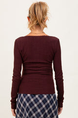 woman wearing a maroon maternity long sleeve top with a fitted style, viewed from the back