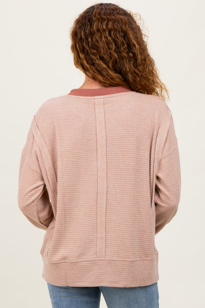 woman wearing a light pink waffle knit top with a relaxed fit and contrasting neckline detail, viewed from the back