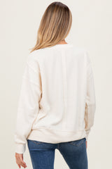 woman wearing a cream-colored maternity sweatshirt with a relaxed fit, showing the back view and casual style