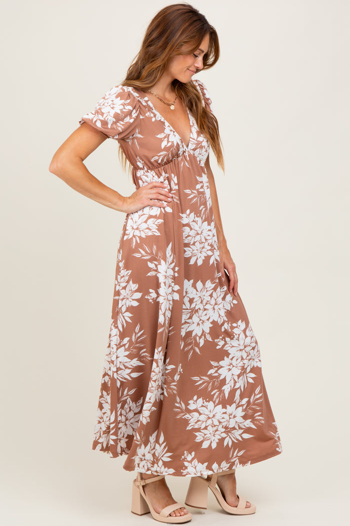 woman wearing a brown floral maxi dress with short sleeves, posing sideways with a soft smile