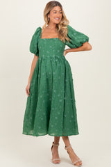 woman wearing a green puff sleeve maternity dress with a square neckline and floral embroidery