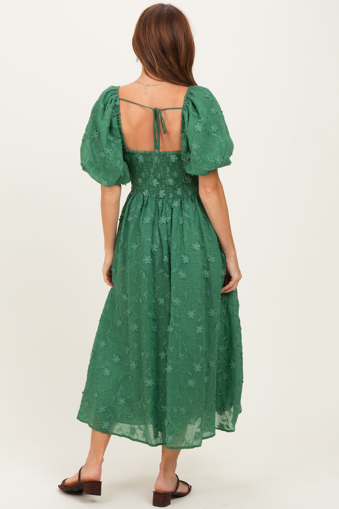 woman wearing a green floral embroidered midi dress with puff sleeves and an open back