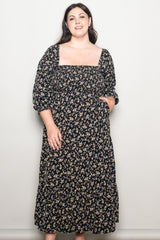 woman wearing a black floral maxi dress with puff sleeves and a square neckline, smiling at the camera