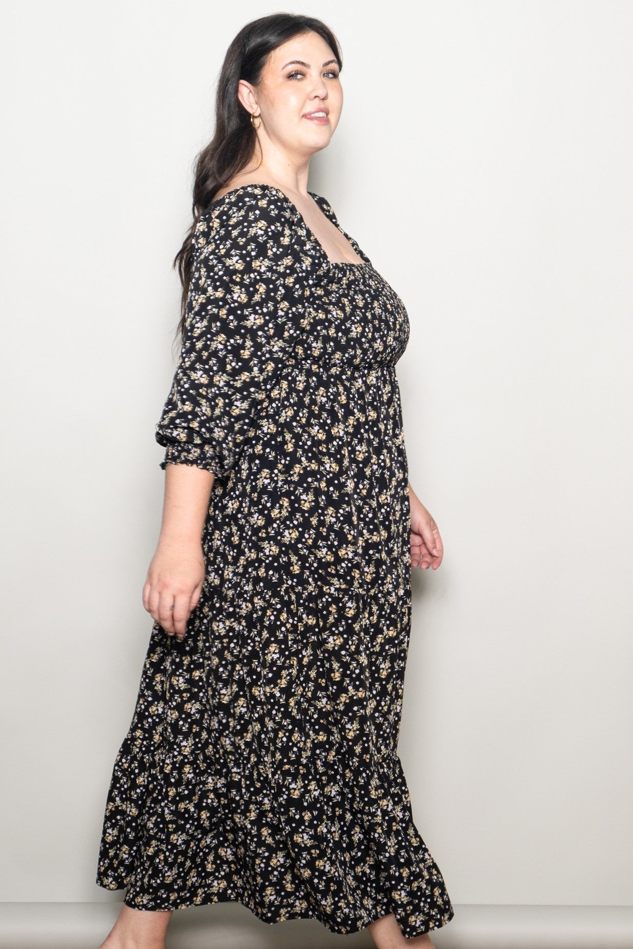 woman wearing a black floral plus-size maxi dress with a square neckline and ruffled hem