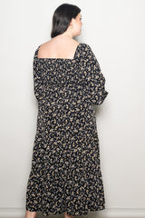 woman wearing a black floral plus size maxi dress with a square neckline and long sleeves, viewed from the back