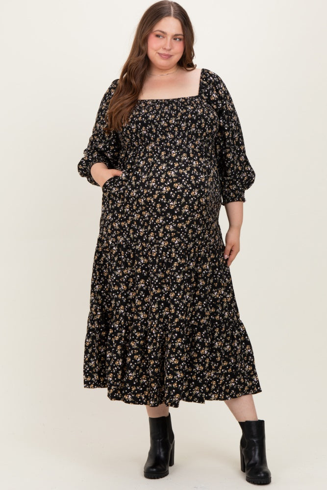 woman wearing a black floral maternity plus dress with a square neckline and puff sleeves, featuring a tiered skirt and pockets