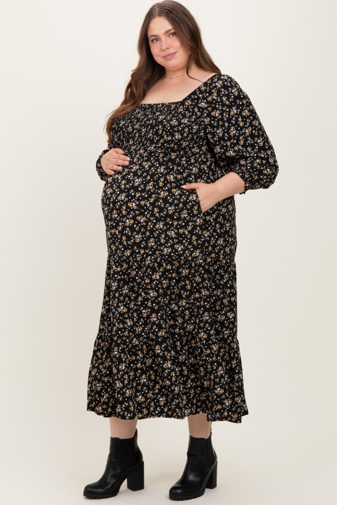 woman wearing a black floral maternity dress with a square neckline and pockets, showing her baby bump
