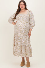 woman wearing a white floral print maternity plus dress with puff sleeves and a tiered skirt, showcasing her baby bump