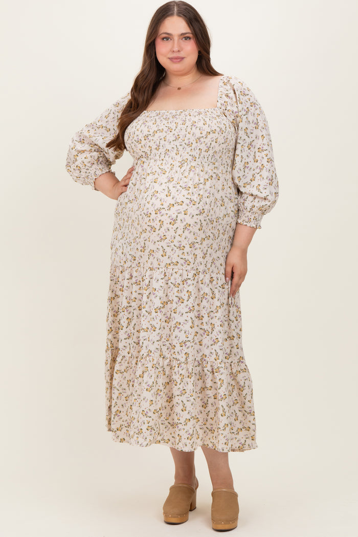 woman wearing a white floral print maternity plus dress with puff sleeves and a tiered skirt, showcasing her baby bump