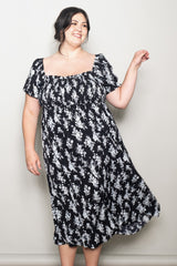 woman wearing a black floral print plus size dress with short sleeves and a square neckline