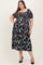 woman wearing a black floral maternity dress with puff sleeves and a midi length, showcasing her baby bump