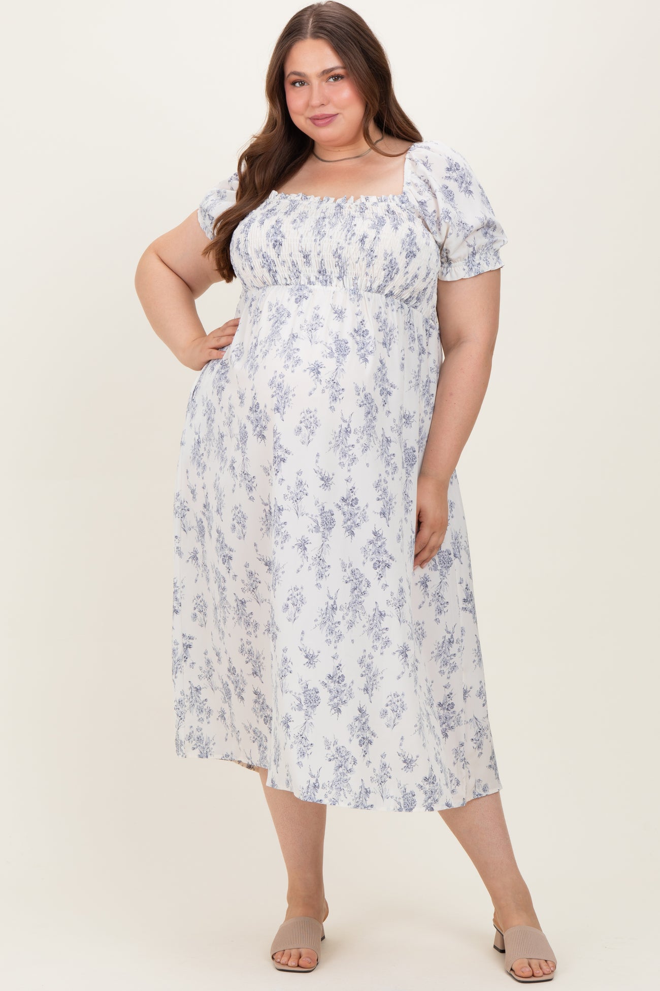 woman wearing a white and blue floral maternity dress with puff sleeves and a square neckline, showing her baby bump