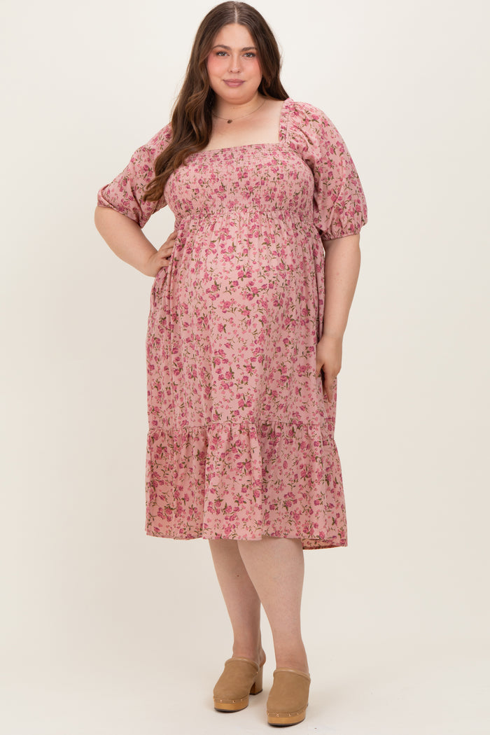 woman wearing a pink floral maternity dress with puff sleeves and a tiered hem, showcasing her baby bump