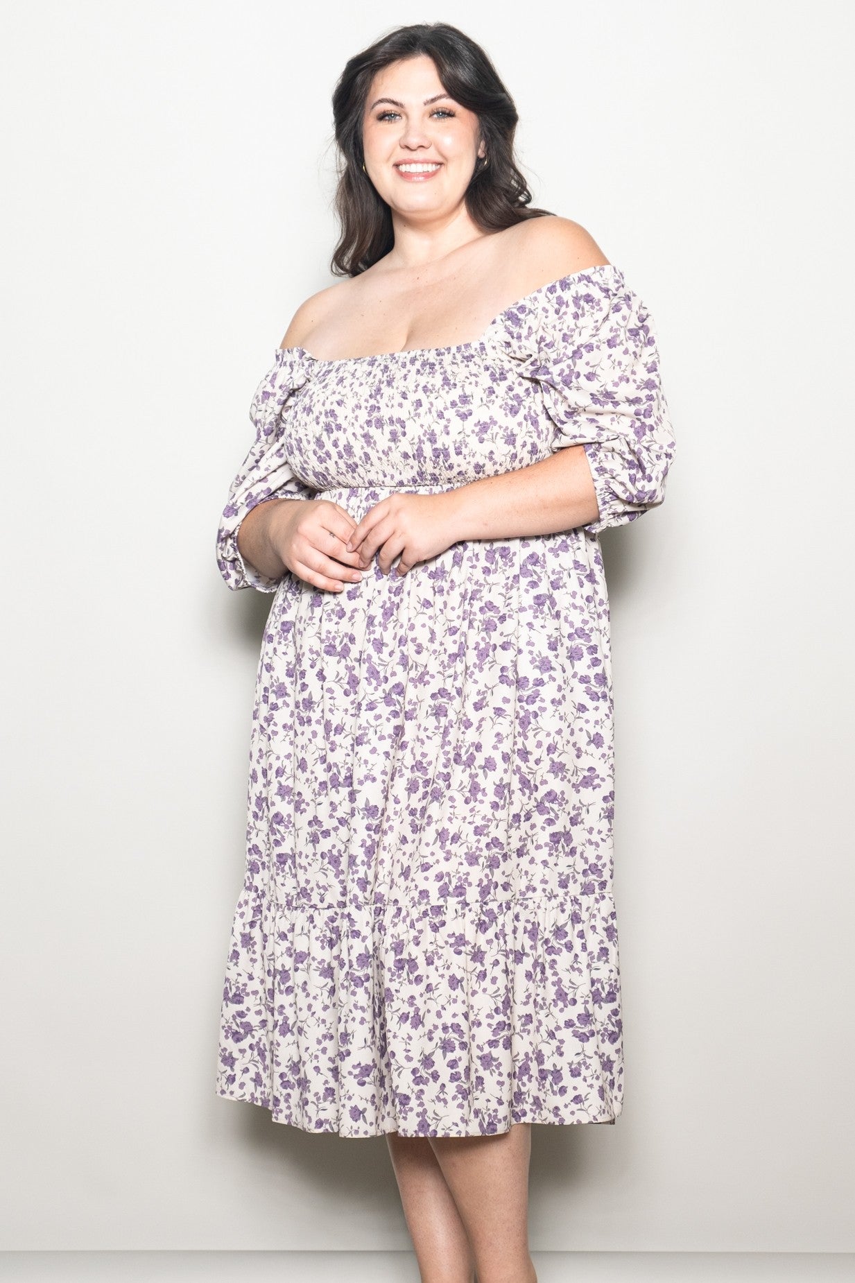 woman wearing a floral off-the-shoulder plus size dress with puff sleeves and a fitted bodice