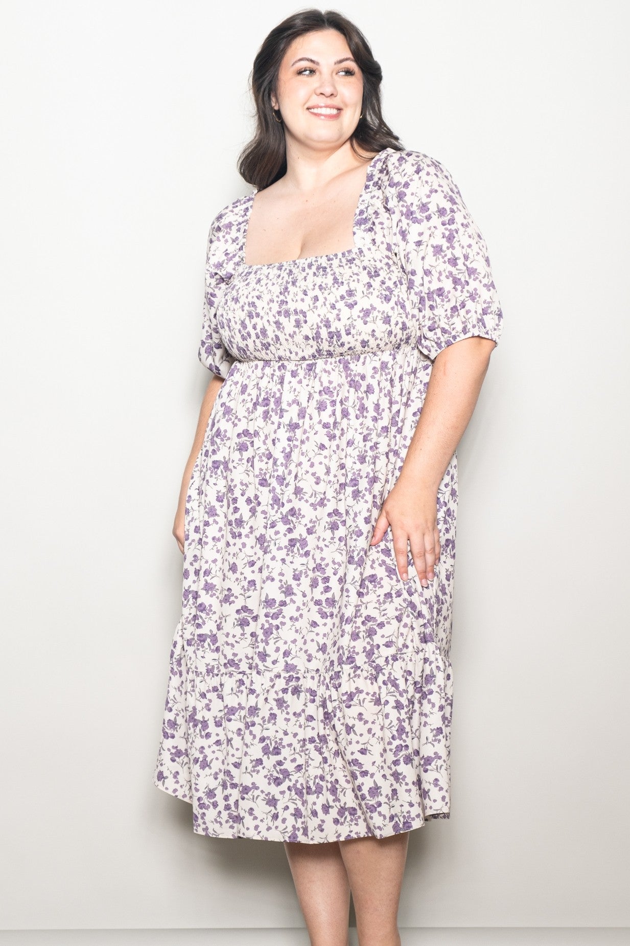woman wearing a purple floral print plus size dress with a square neckline and short puff sleeves