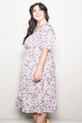 plus size woman wearing a purple floral midi dress with short sleeves and a cinched waist