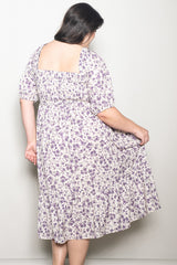 woman wearing a plus-size cream and purple floral print dress with a smocked back and puff sleeves