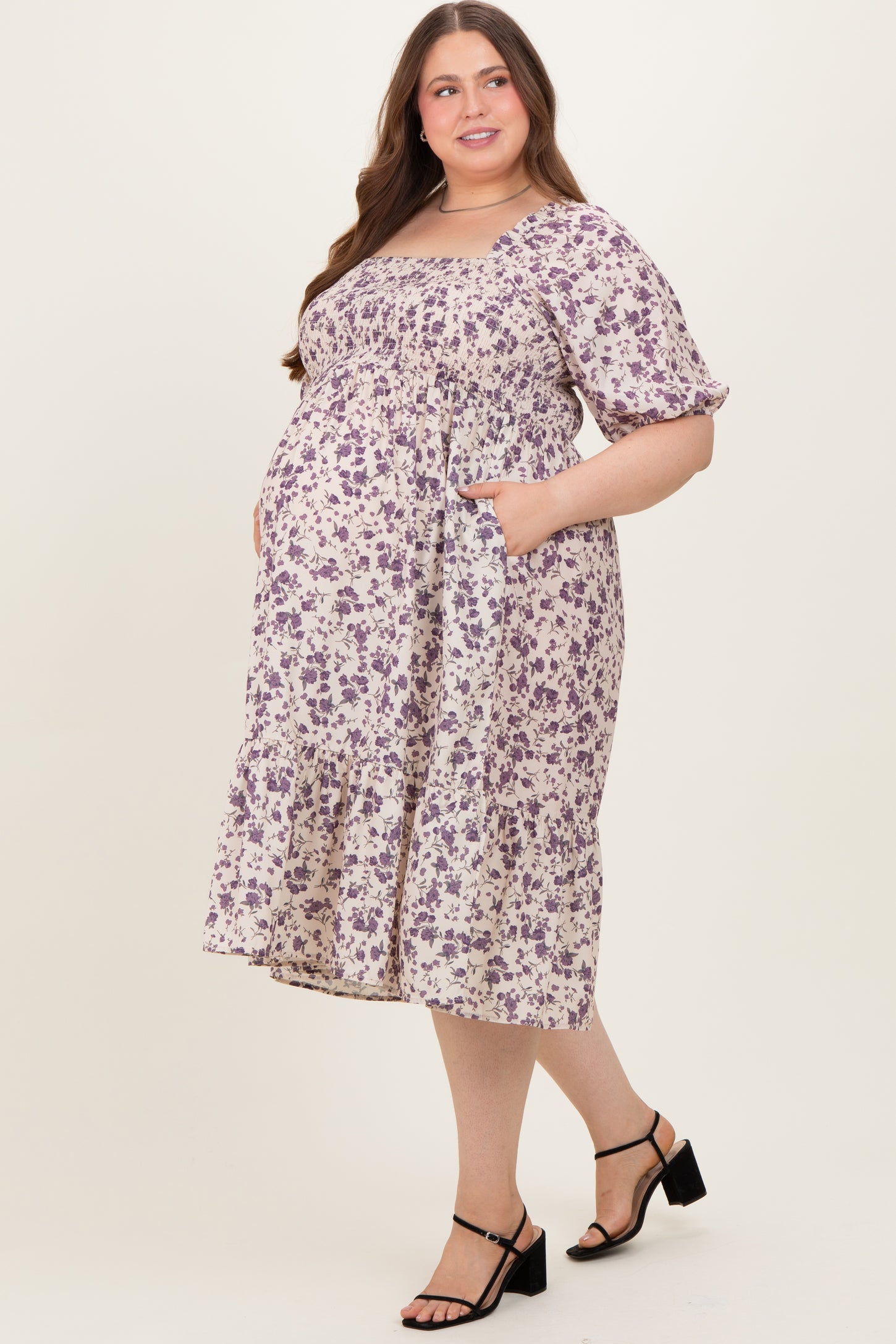 woman wearing a floral print maternity plus dress with short sleeves and pockets, showing her baby bump