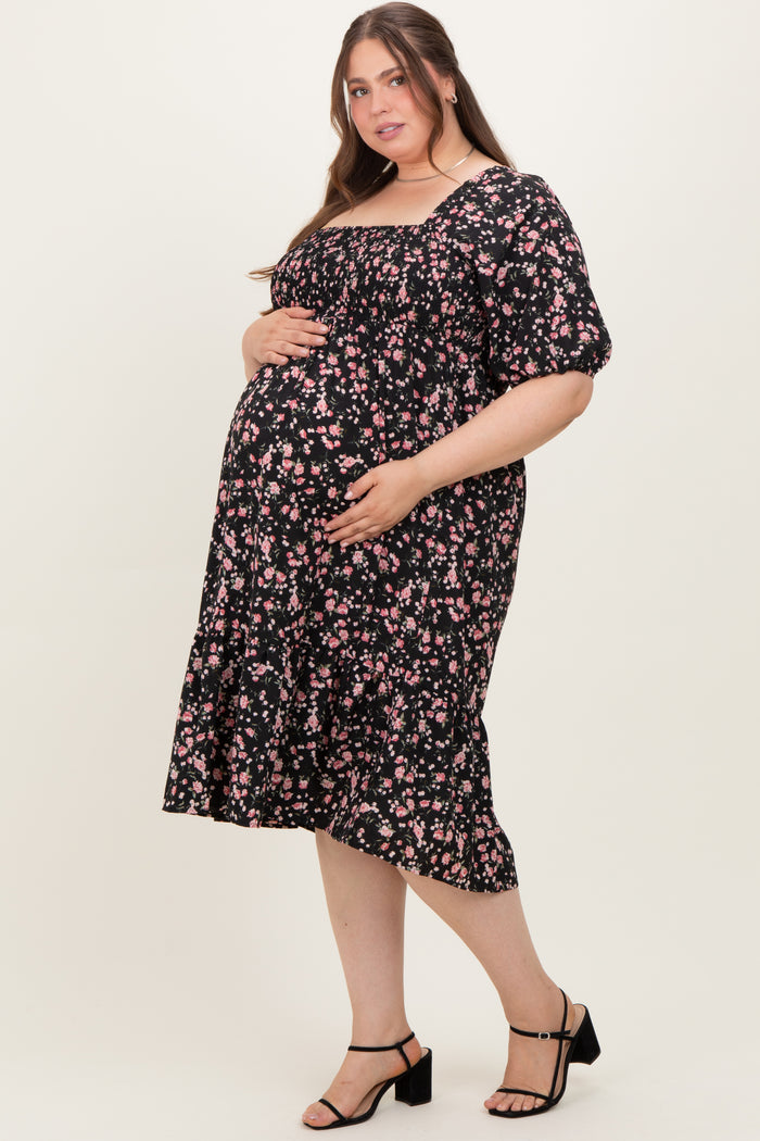 woman wearing a black floral maternity dress with a ruffled hem and puff sleeves, showcasing her baby bump