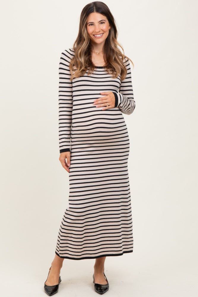 woman wearing a black and cream striped maternity maxi dress and holding her baby bump